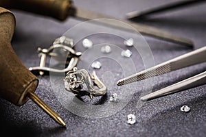 Earrings with a stone on the table, surrounded by tools for the repair of jewelry