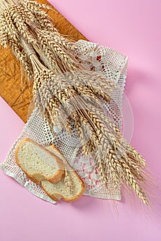 Ears of wheat and white bread rusks on a wooden board from above