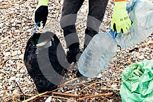 Earth Day. An activist picks up plastic trash. The concept of environmental protection and cleaning of the coastal zone.