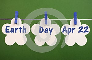 Earth Day, April 22, message greeting written across white flower cards hanging from pegs on a line