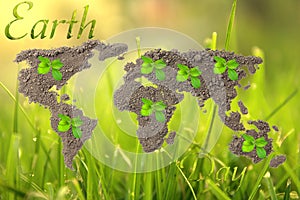 Earth Day. Concept ecology. World map, globe from the soil with green plants around the world on natural background