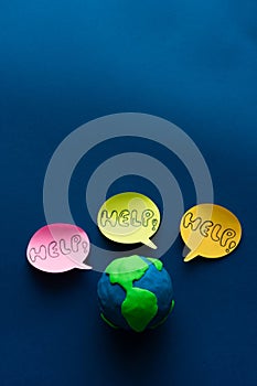 Earth Day. Globe on blue background with three HELP messages. Space copy. Vertical photo
