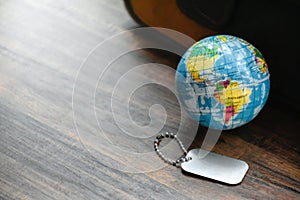 Earth Globe and Dog Tag on wood pattern work desk and soft sunlight background,World and map of Americas,Dog Tag empty,Desktop