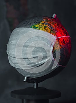 Earth globe with medical mask on dark background, global pandemic covid-19, coronavirus