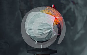 Earth globe with medical mask on dark background, global pandemic covid-19, coronavirus