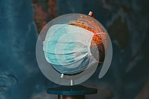 Earth globe with medical mask on dark background, global pandemic covid-19, coronavirus