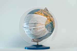 Earth globe with medical mask on white background, global pandemic covid-19, coronavirus