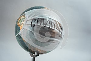 Earth globe with medical mask on white background, global pandemic covid-19, coronavirus
