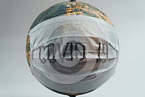 Earth globe with medical mask on white background, global pandemic covid-19, coronavirus