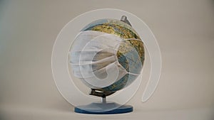 Earth globe with medical mask on white background, global pandemic covid-19, coronavirus