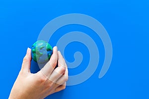 Earth. Hand hold plastiline symbol of planet Earth globe on blue background top view copy space