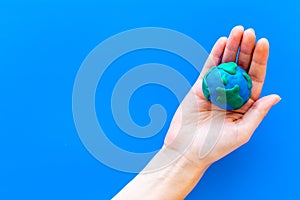 Earth. Hand hold plastiline symbol of planet Earth globe on blue background top view copy space