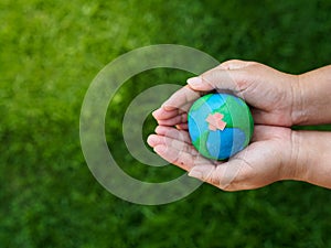 Earth in hands and green grass field background. environment sav