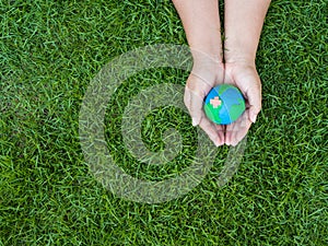 earth in hands and green grass field background. environment save earth concept.