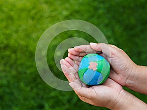 Earth in hands and green grass field background. environment sav