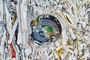 Earth model sinking into waste paper