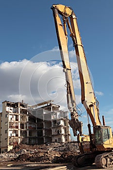 Earth mover demolishing ruins