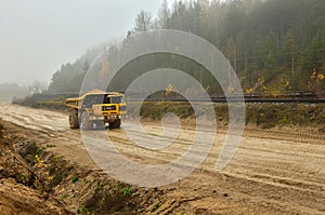 Earth mover loading dumper truck with sand in quarry. Excavator loading sand into dumper truck.Quarry for the extraction of minera photo