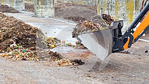 Earth mover working with pile of compost at plant