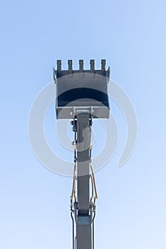 earth moving machine's arm and bucket isolated on blue sky