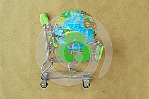 Earth planet in green shopping cart with recycle symbol on recylced paper - Concept of ecology and responsible shopping photo