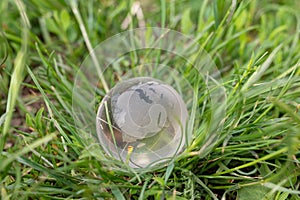 Earth planet symbol on background of green grass. Glass ball on nature backdrop. ecology concept, environment conservation
