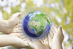 Earth in shape water drop from the top of the children hand on green background for international water day concept or world
