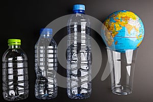 Earth world globe and plastic bottle waste on the black background.Saving the planet Earth from plastic bags concept.Global