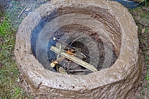 Earthen firing chamber, the replica of an ancient pit fire kiln, with lit twigs