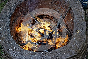 Earthen firing chamber, the replica of an ancient pit fire kiln, with lit twigs and larger branches