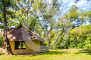 Earthen house under shade of trees. An earth house, also known as earth berm, earth sheltered home, or eco-house is an architectur