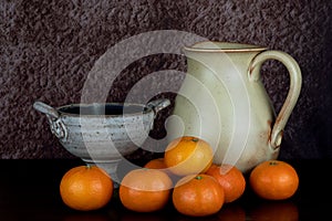 Earthenware Chalice Bowl and Wine Jug with Satsuma Oranges on a Wooden Surface