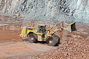 Earthmover in an active quarry mine of porphyry rocks. digging.