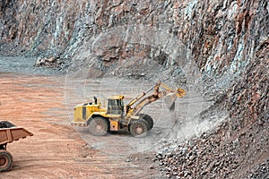 Earthmover in a open pit mine quarry. porphyry rock