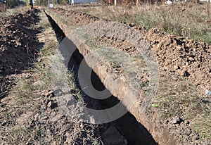 Earthworks, digging trench. Long earthen trench dug to lay pipe photo