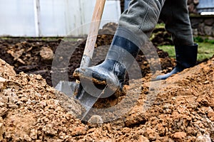 Earthworks, man digging trench using shovel.