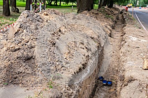 Earthworks, trench digging. A long earthen trench is dug for laying pipes. Repair in the city