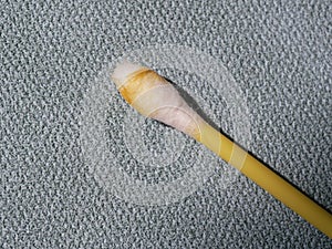 Earwax on a cotton swab, macro photo. Earwax, also known by the medical term cerumen, is a brown, orange, red, yellowish or gray