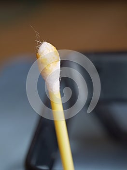 Earwax on a cotton swab, macro photo. Earwax, also known by the medical term cerumen, is a brown, orange, red, yellowish or gray