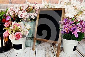 Easel blackboard empty mock up space for copy with flower decoration on wooden background