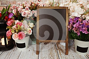 Easel blackboard empty mockup space for copy with flower decoration on wooden background