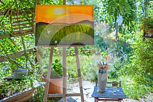 Easel with canvas art painting outdoors in a garden. Mindfulness, art therapy and creative hobbies concept.