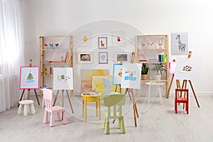 Easels with paintings and chairs for children