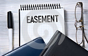EASEMENT - word in white paper on the background of a diary, glasses and pen