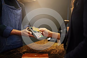 Easier than swiping. a customer paying using NFC technology in a shop.