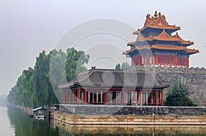 East corner of Palace Museum at the Forbidden City and surrounding moat filled with water with dramatic cloudscapes in Beijing Ch