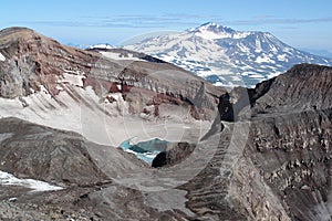 The east crater of Gorely volcano with blue acid lake covered partially with ice in august