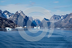 East Greenland coast with jagged mountains, icebergs and blue sea