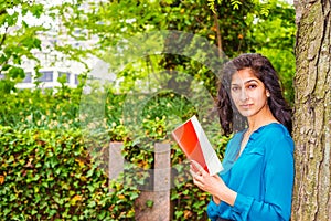 East Indian American college student reading book outside in New