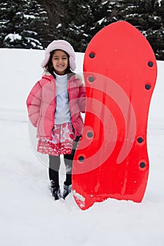 East Indian girl toboganning in the snow